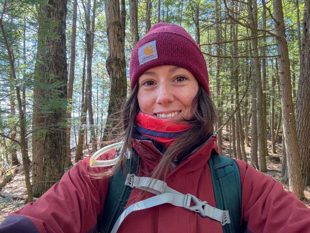 Young adult outdoors smiling at a camera.